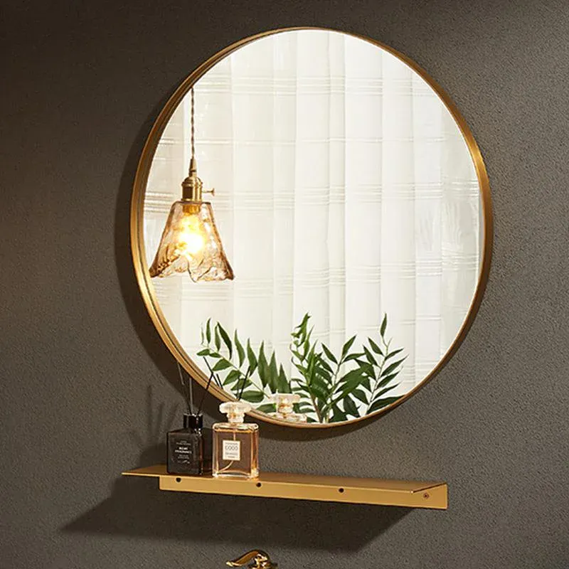 Gold-framed round mirror installed above a shelf